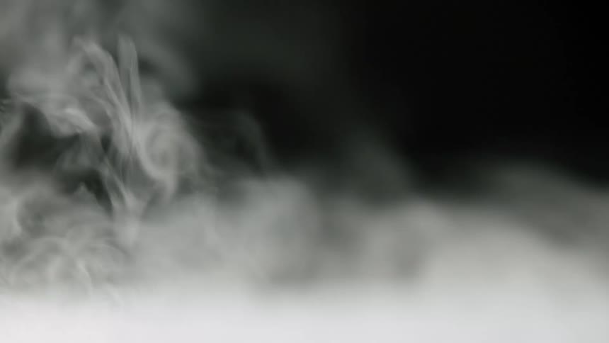 White vapor floats through air against black background