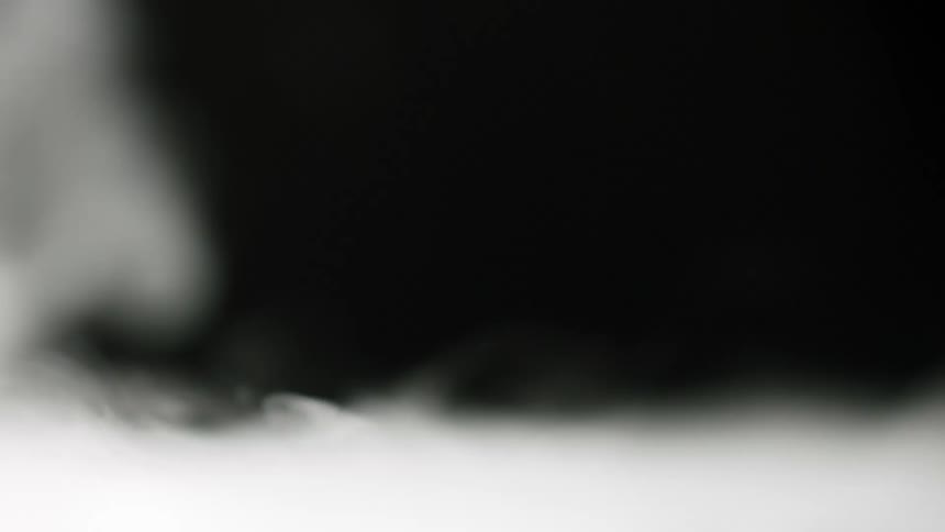 White dry ice smoke rises against black background