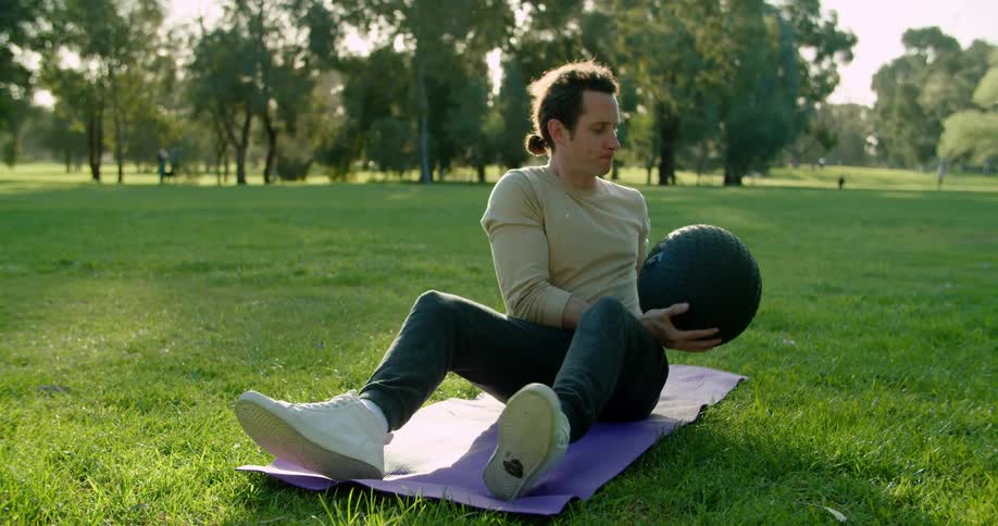 A man is lifting a ball up and down to exercise
