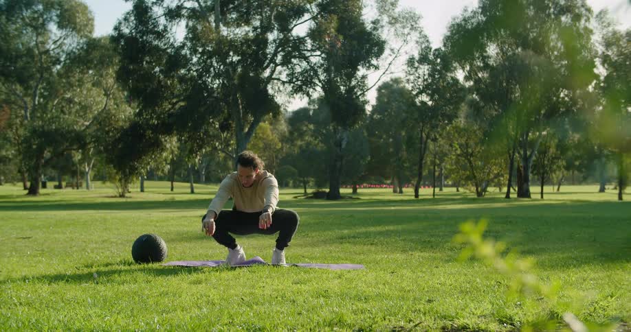 Man warms up before working out on green grass in the public park