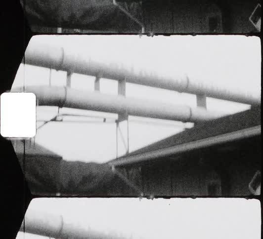 A pair of large pipes pass over the roof of a building during the day