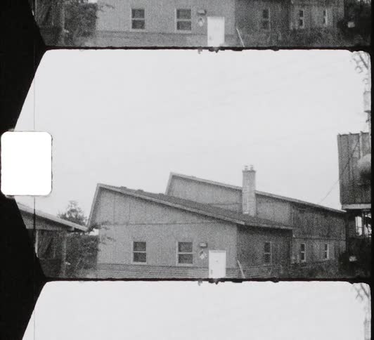 Black and white footage of a house in a neighborhood caught on film