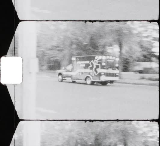 Ambulance drives past building and marked parking spots