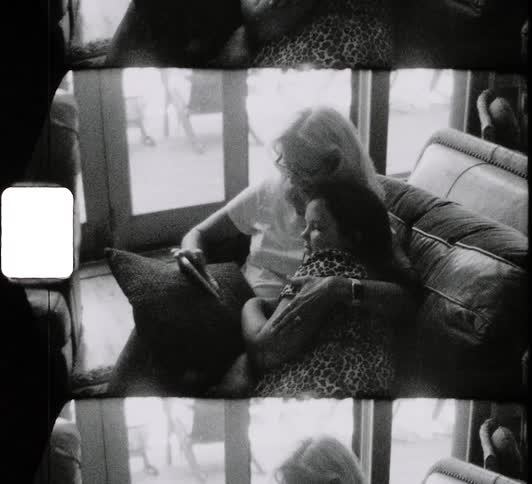 A woman and a girl sitting on a couch hugging and looking at a smart phone