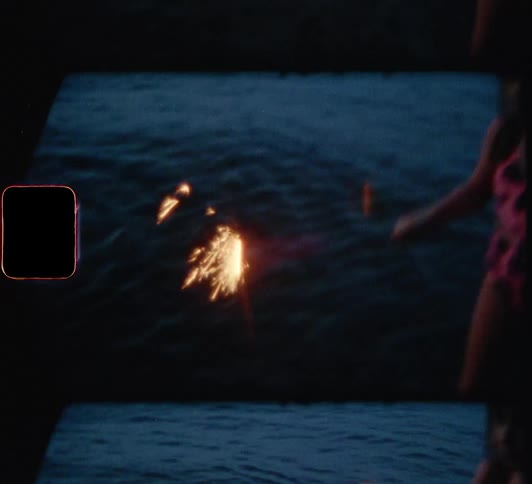 Little girls play with sparklers in water at dusk