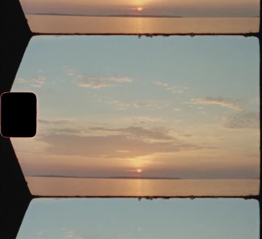 The sun sits on the horizon across the ocean 8mm