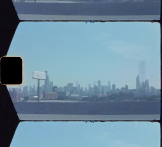 Big city skyline from a distance with high rise buildings and skyscrapers on the horizon seen from a moving car 8mm