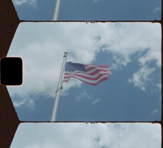An american flag waves atop a flag pole on a bright day 8mm