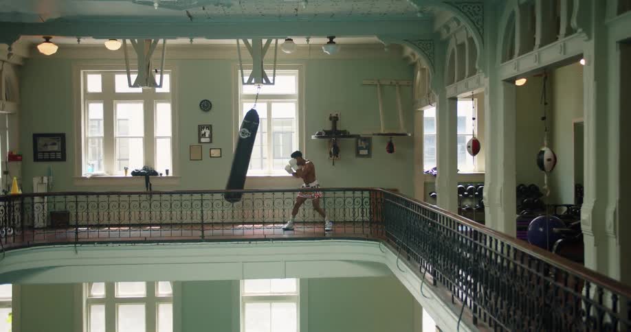 A man punches a punch bag hanging on an upper floor of a building