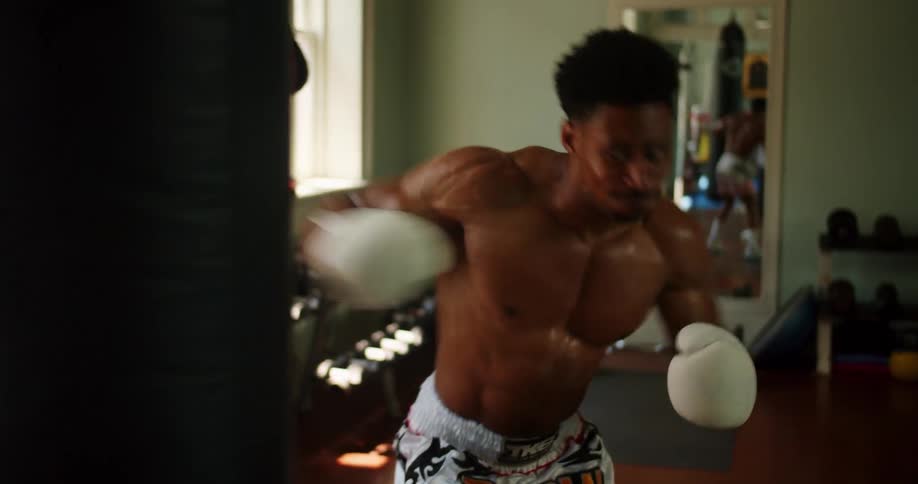A young man fiercely punches a boxing bag