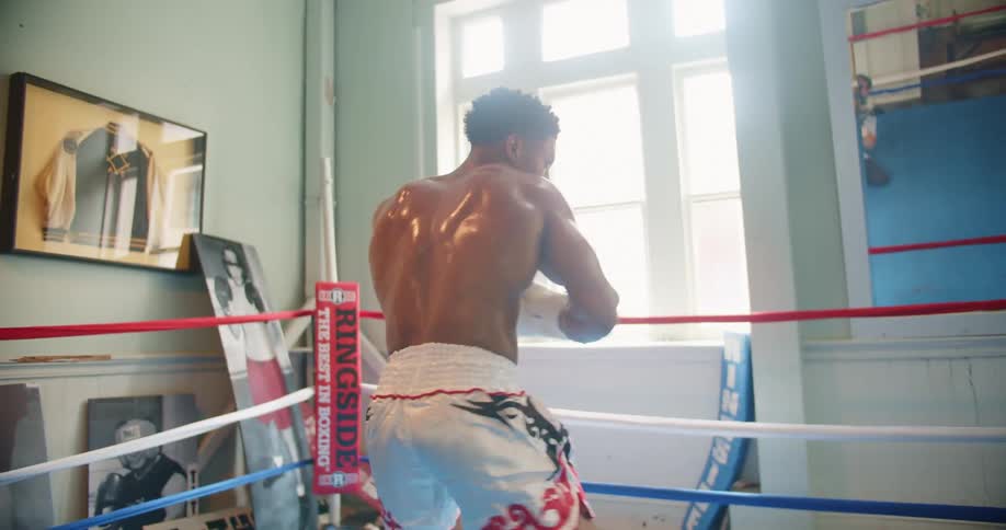 Muscular male boxer throws punches in the boxing ring