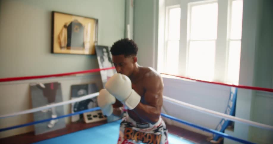 A man practices boxing jabs while standing in a boxing ring by himself