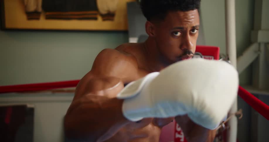 A man in a boxing ring throws punches in the air