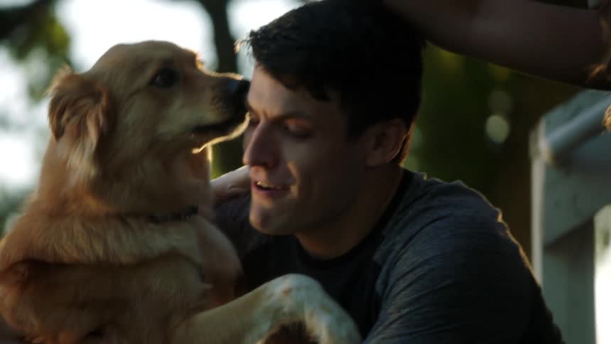 A man and woman feed a treat to a dog