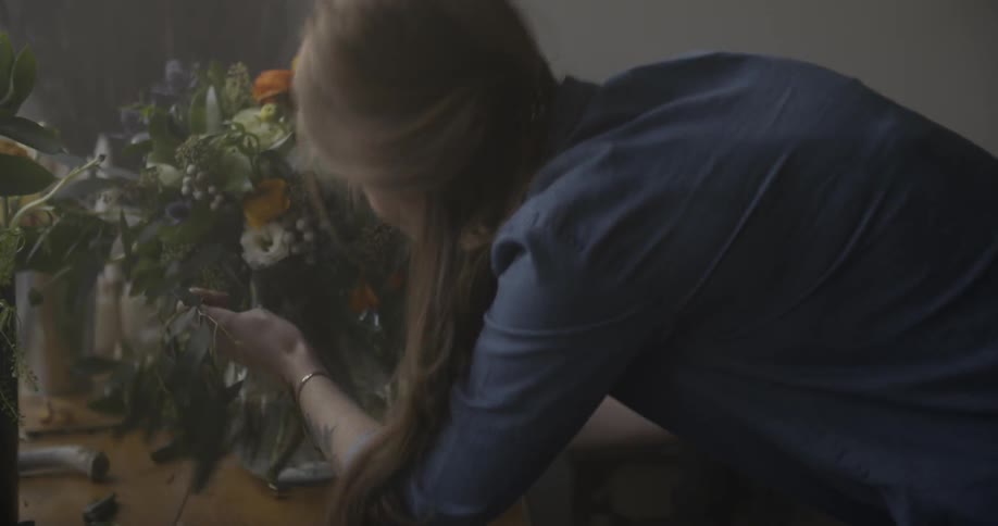 A woman arranges flowers in a vase