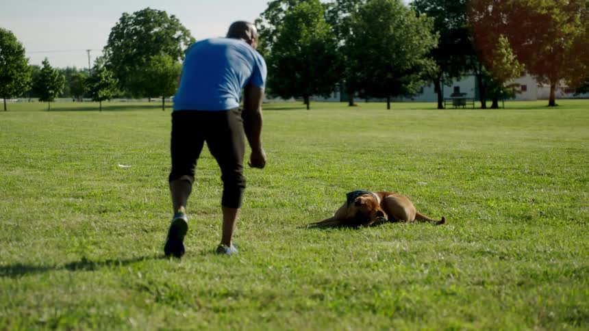 A man is playing outdoors with his dog