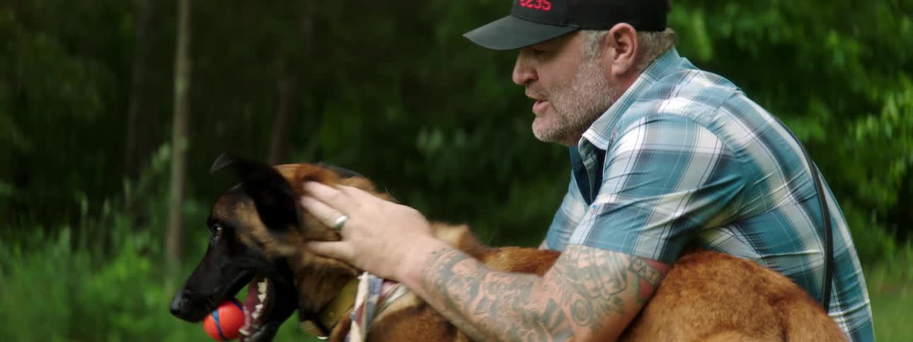 A man is petting his dog outdoors