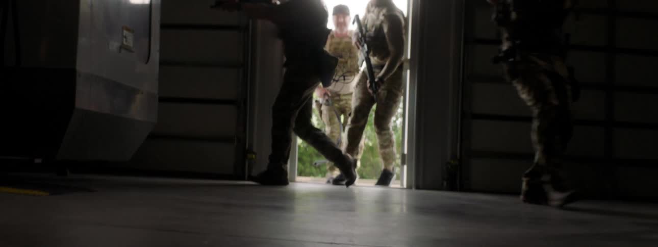 A k9 is released into a building through an open door and a tactical unit enters behind with weapons drawn