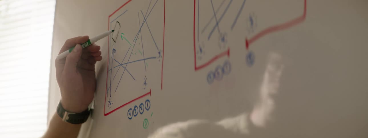 A man uses a marker to draw a chart on a whiteboard