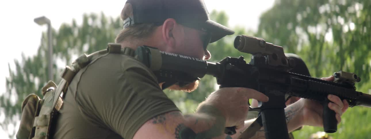 Group of police or military men carrying assault rifles and a dog on a training exercise in a neighborhood