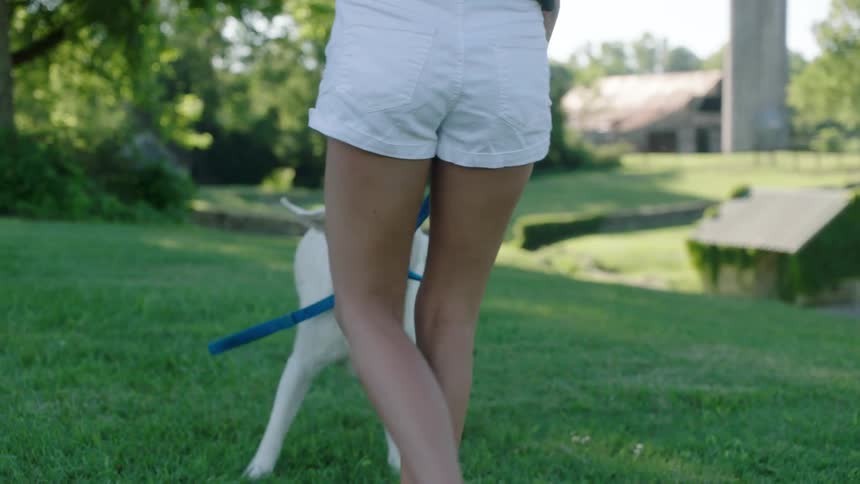 A pretty white woman laughs while playing with her dog on a farm