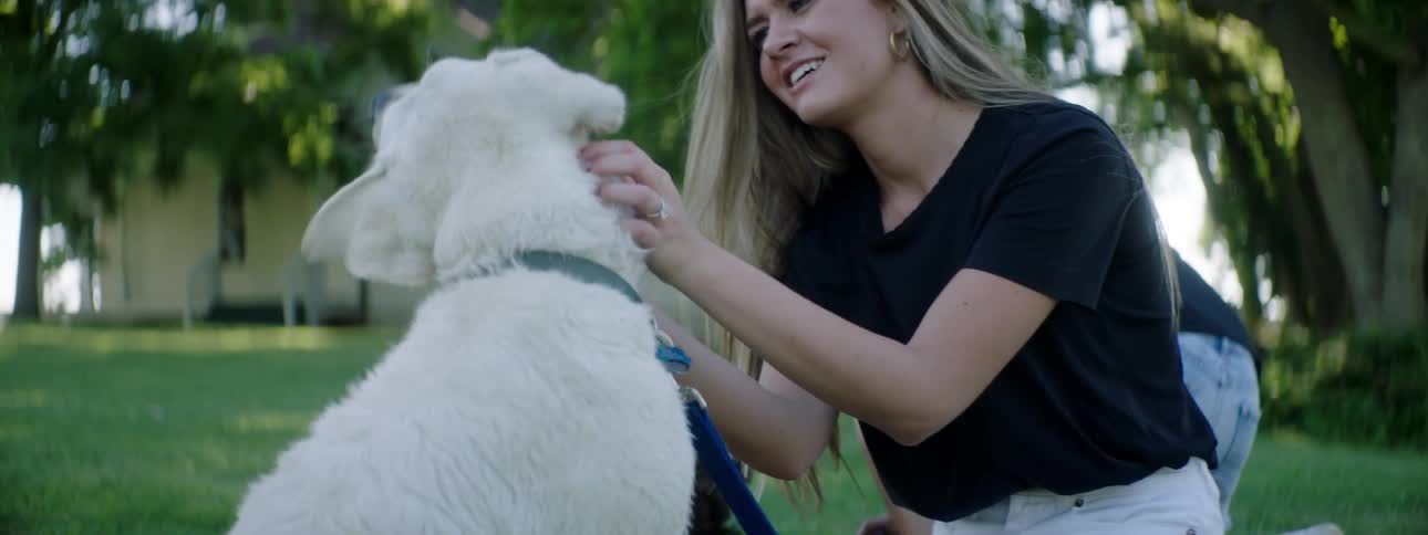A woman is petting her white dog