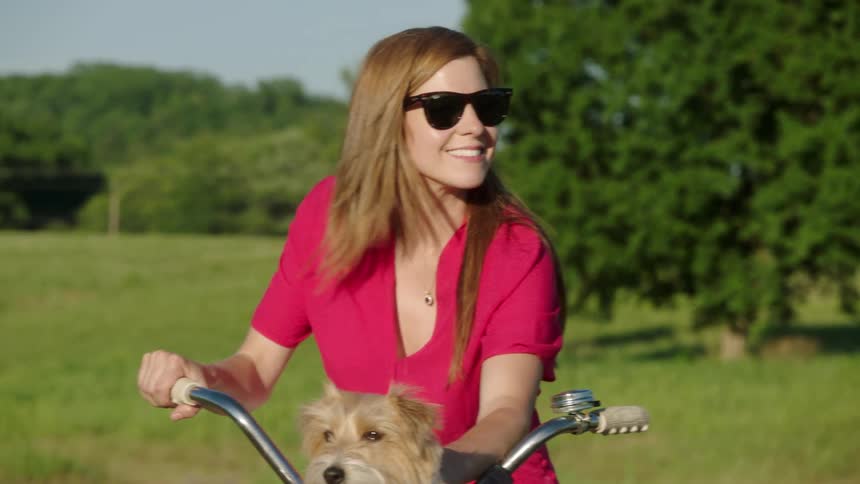 A female with a dog on her bike riding a bike outside
