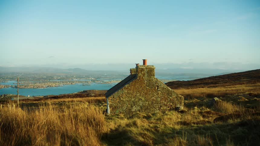 Very old stone house on hillside overlooking lake