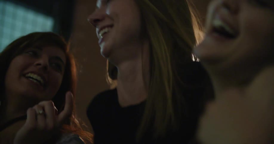 Women walk past building at night laughing