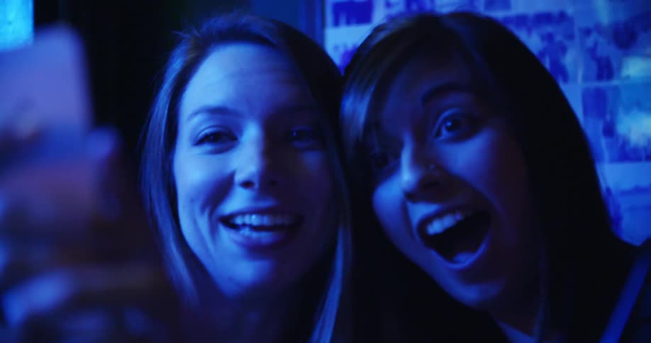 Two teenage girls take a selfie on a cell phone