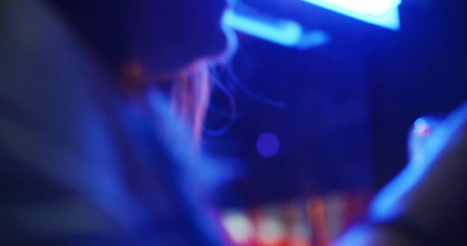 Two women in a bar drink and one looks at pictures on her phone