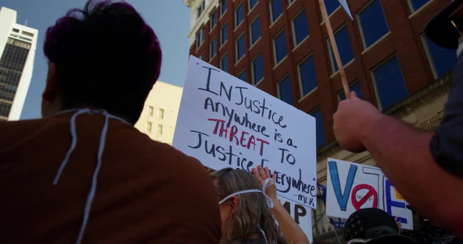 A group of protesters hold signs in the air as they march down a city street during the day