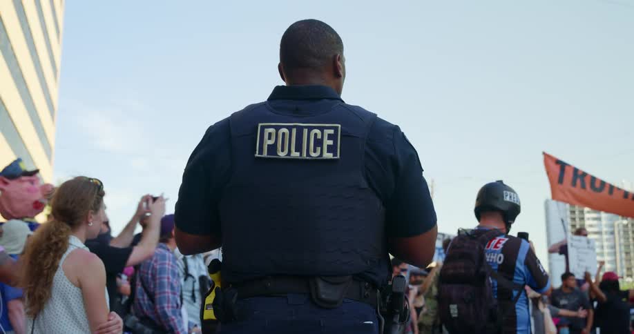 Police monitor a large group of people at a protest