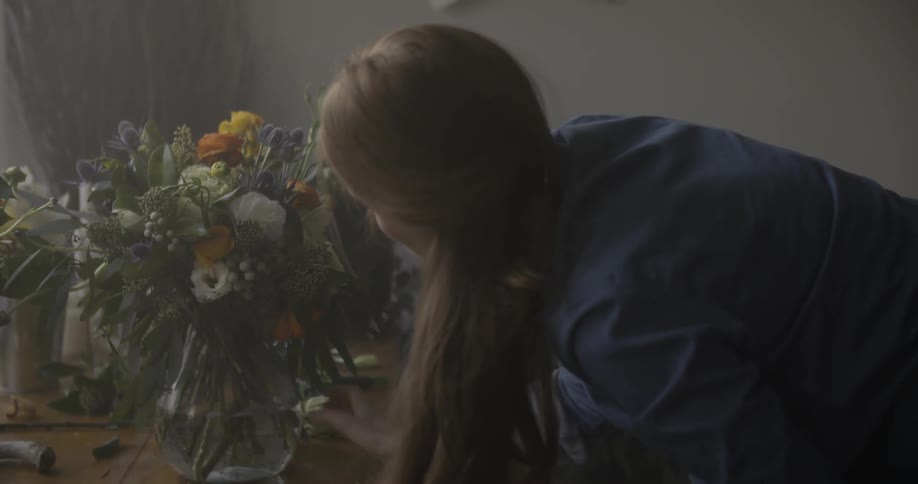 A woman is carefully arranging a bouquet of flowers