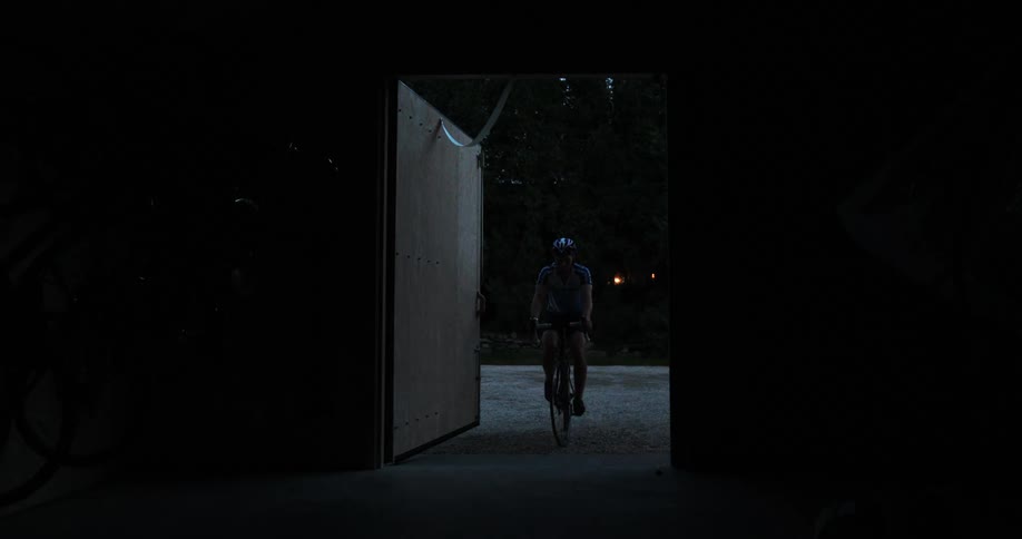 A man bikes up to a building and gets off his bike