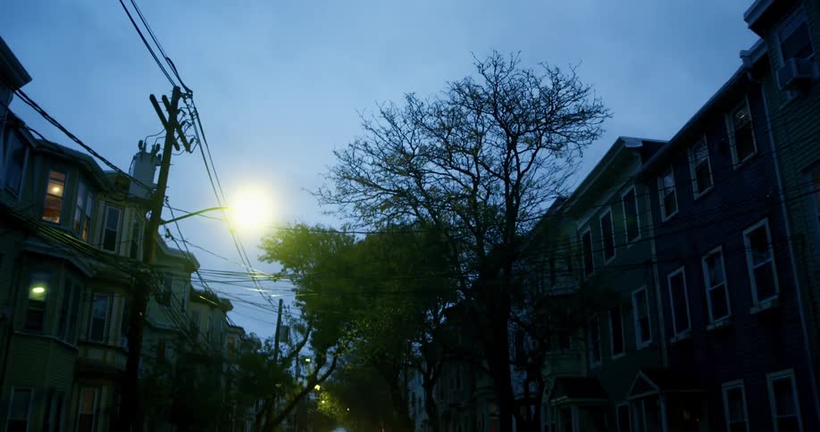 Cars drive down the city street in a neighborhood at night