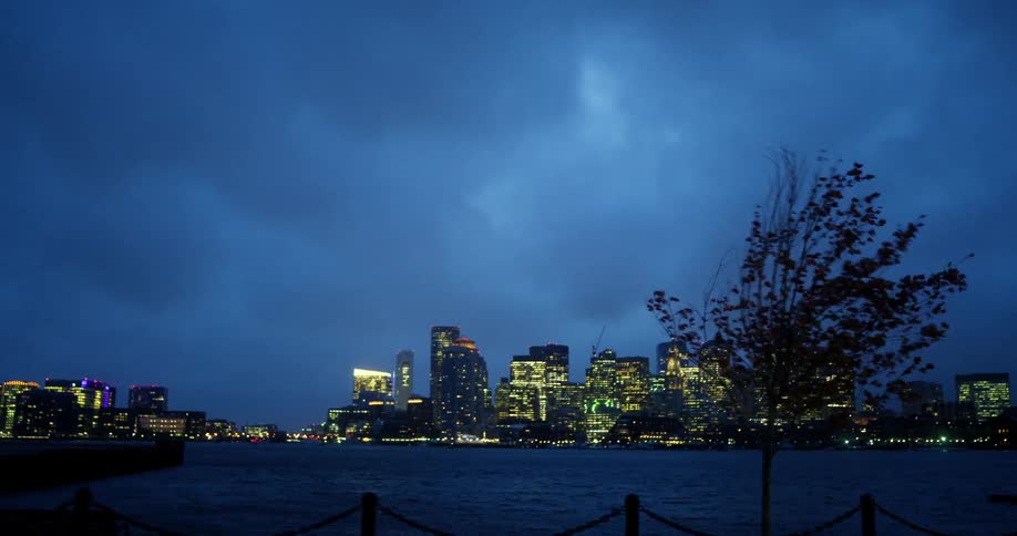 City skyline with illuminated high rise buildings and skyscrapers seen from a distant vehicle at dusk