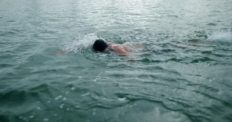 A man swims outdoors in the ocean during the day