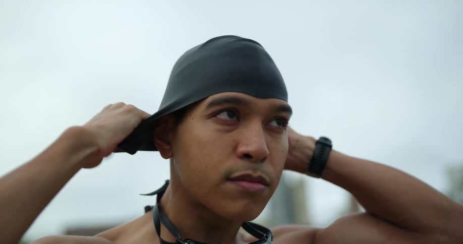 A male placing a swim cap on his head