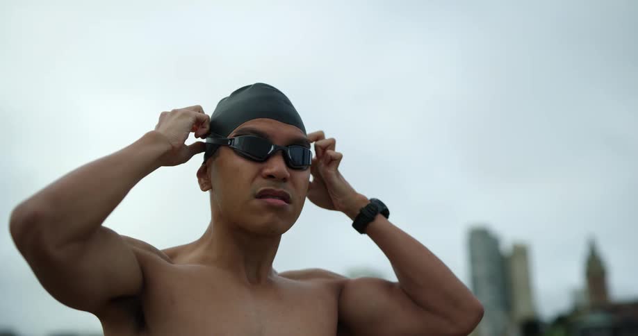 Swimmer dons swimming goggles with skyline on horizon