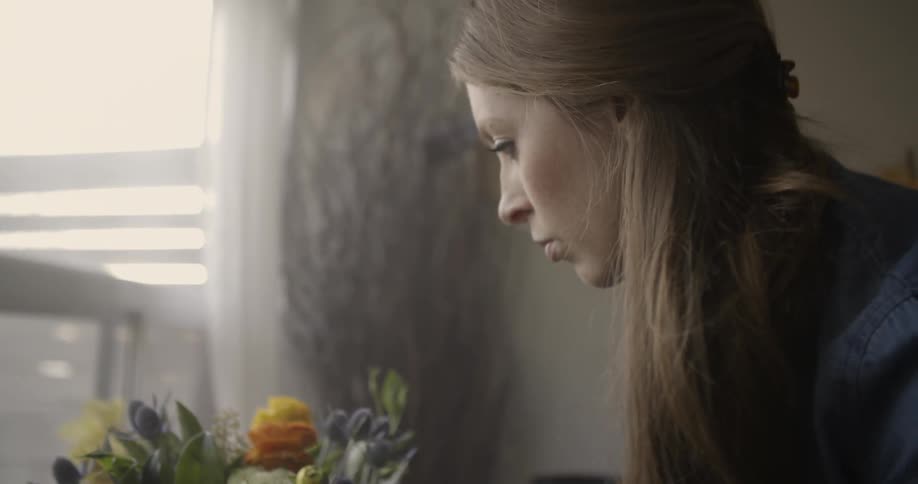 A woman places a vase full of flowers onto a table