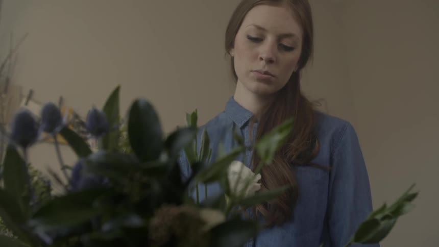 A woman arranges flowers in a vase