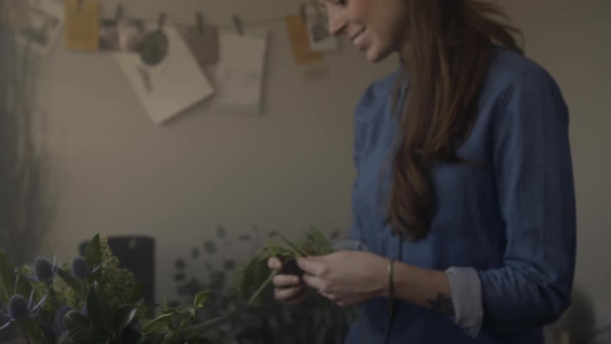A smiling woman holds a bunch of green leaves