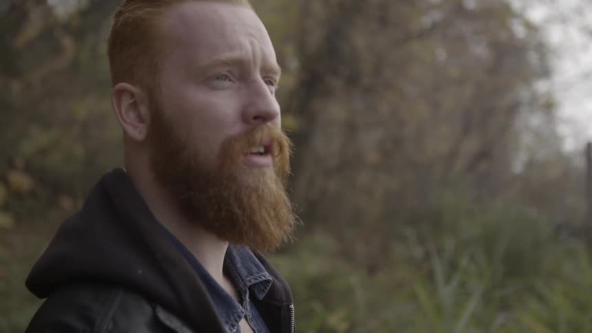 A bearded man looks worried as he stands outside
