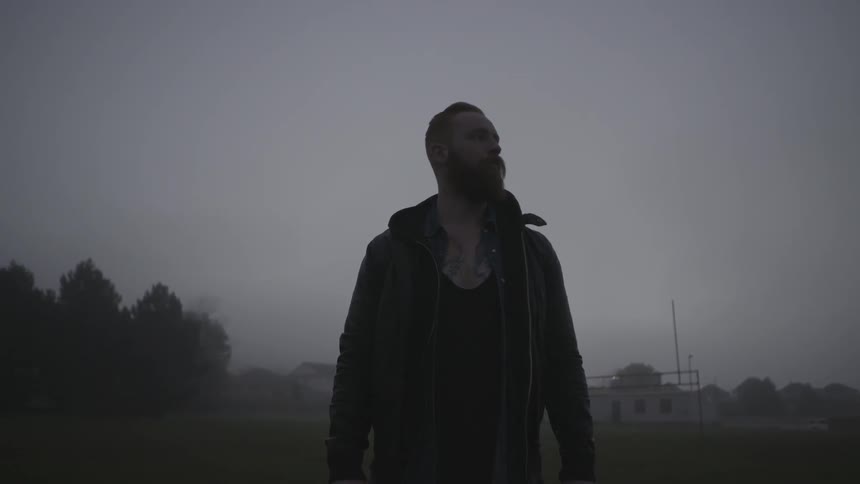 A man stands in the middle of a field on an overcast day