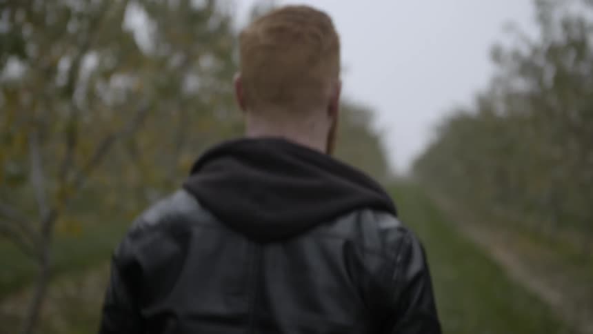 A man walks past trees on an overcast day
