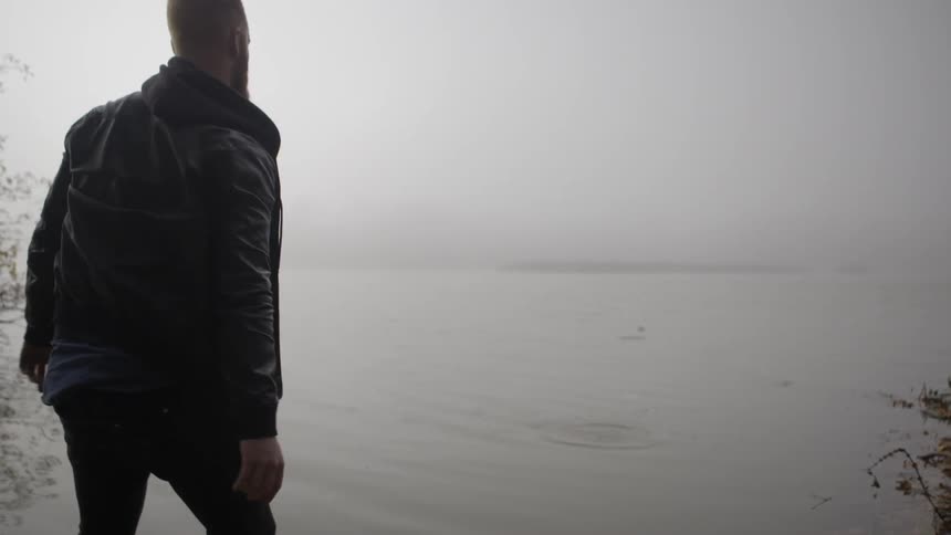 A man tries to skip a rock on a pond