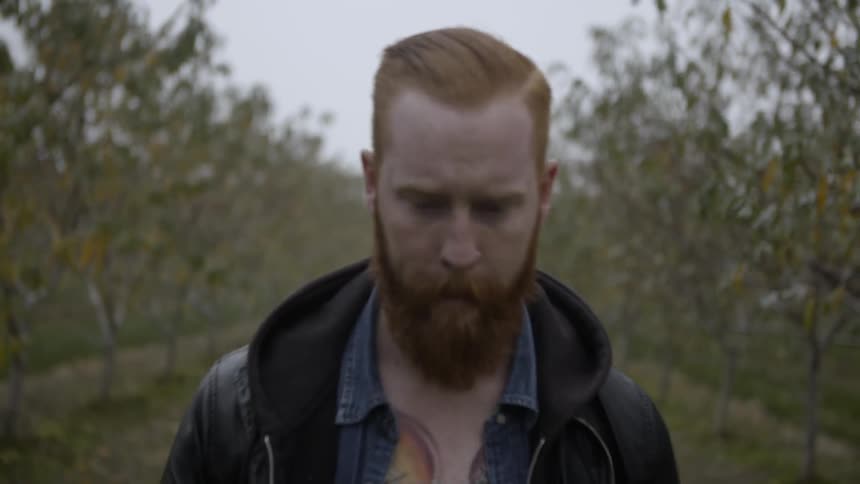 A man is hiking in a field with trees all around