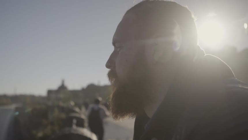 A bearded man sits outside in the sun