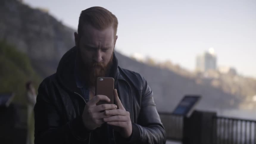 A man with a beard takes pictures with his camera